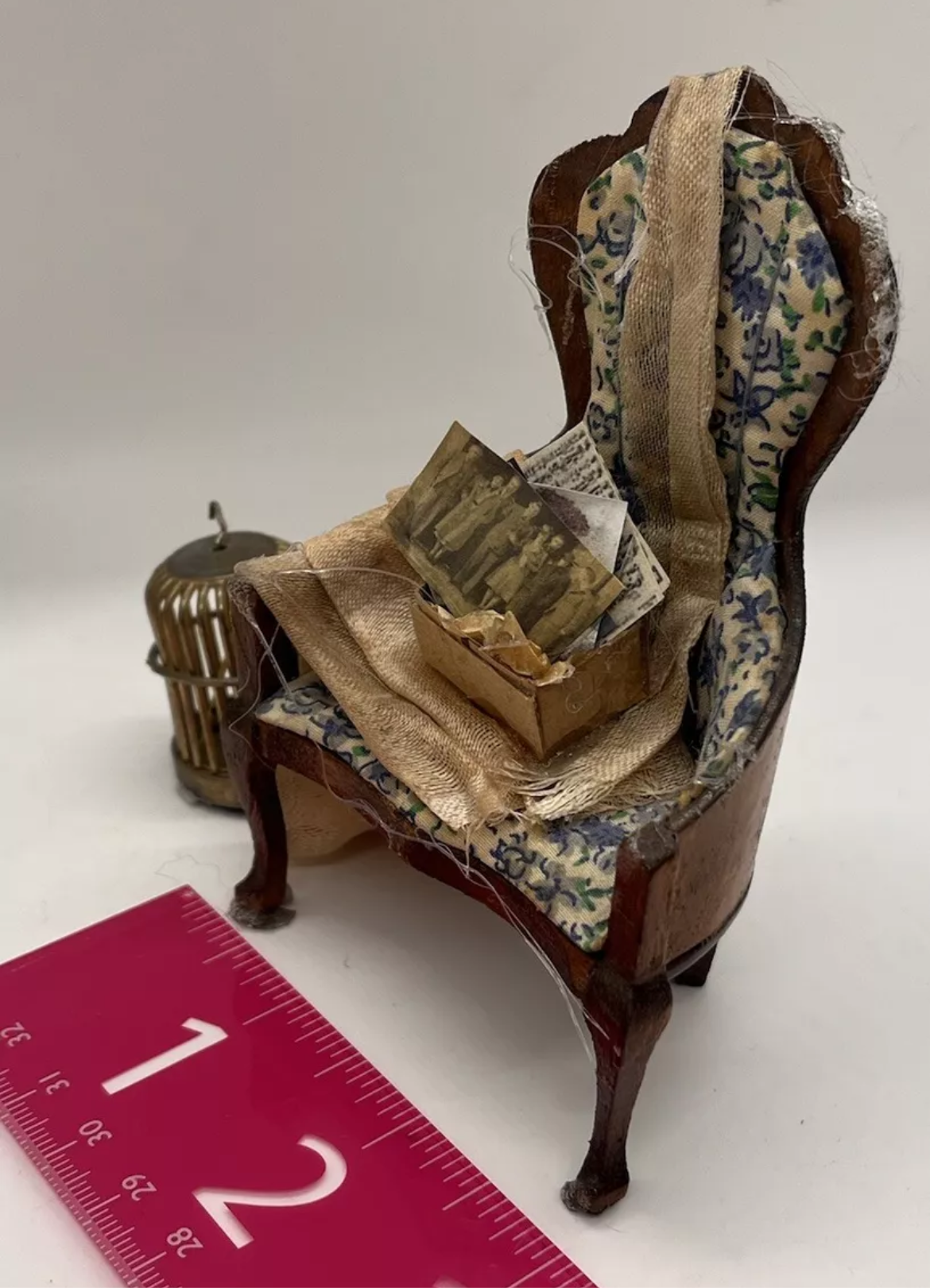 Dolls house old attic loft items, dusty backdrop. Old chair bird cage.