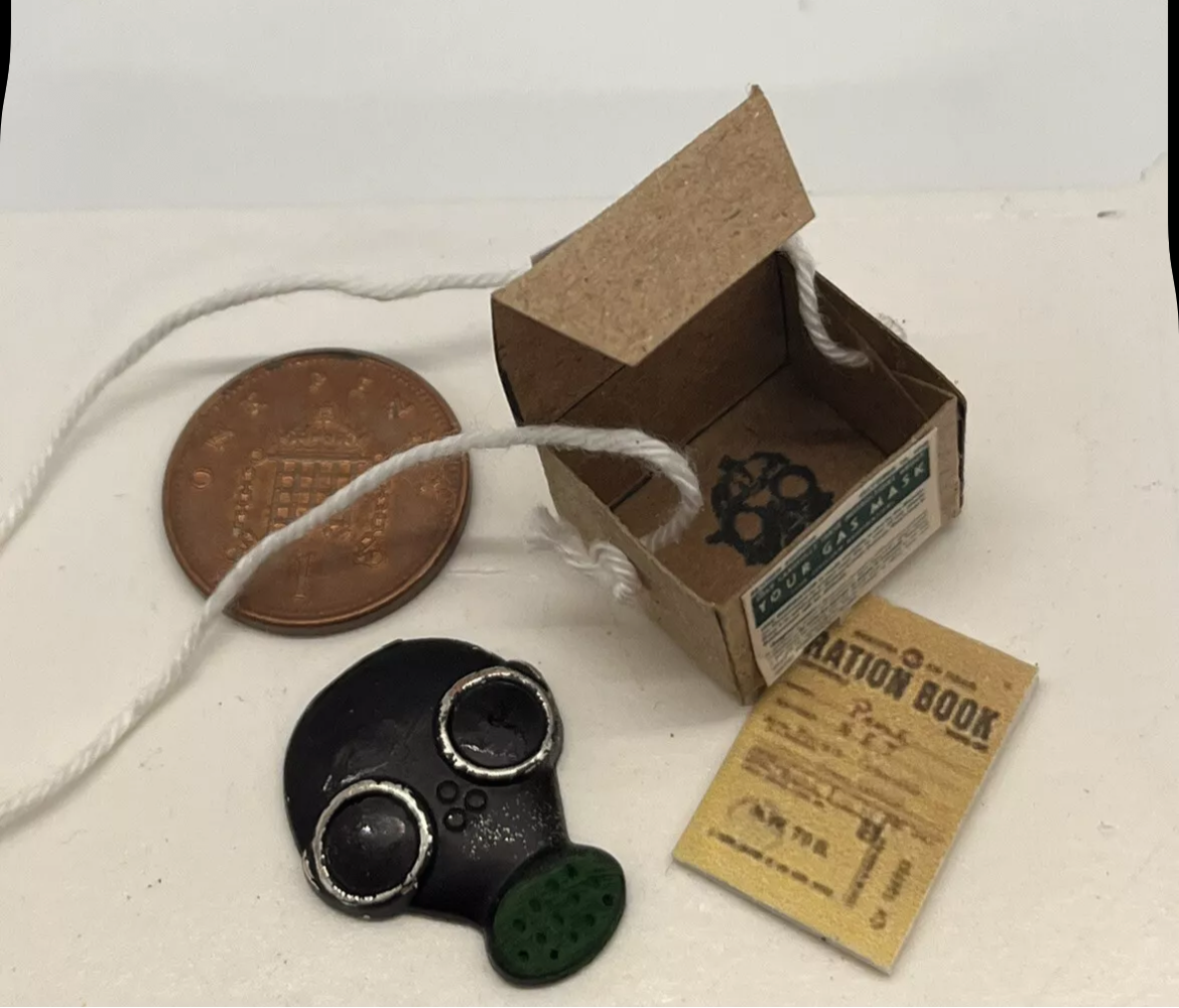 Dolls house has mask, ration book and gas mask box. (New)